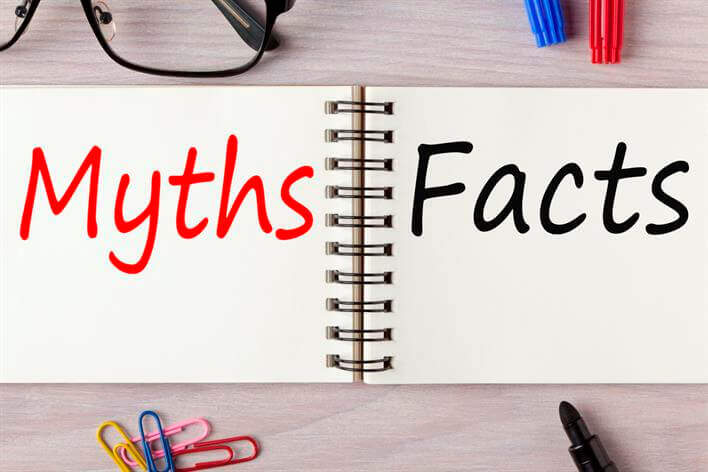 Open notebook displaying the words "Myths" in red and "Facts" in black, surrounded by glasses, pens, paperclips, and a marker – an essential guide at any walk-in clinic.